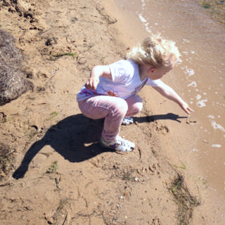 Barn i vandkanten, der rører ved vandet